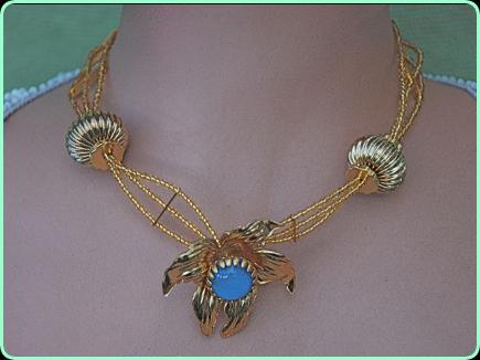 Pretty designer gold beaded three strand necklace with eye catching large gold floweer with a blue stone centre